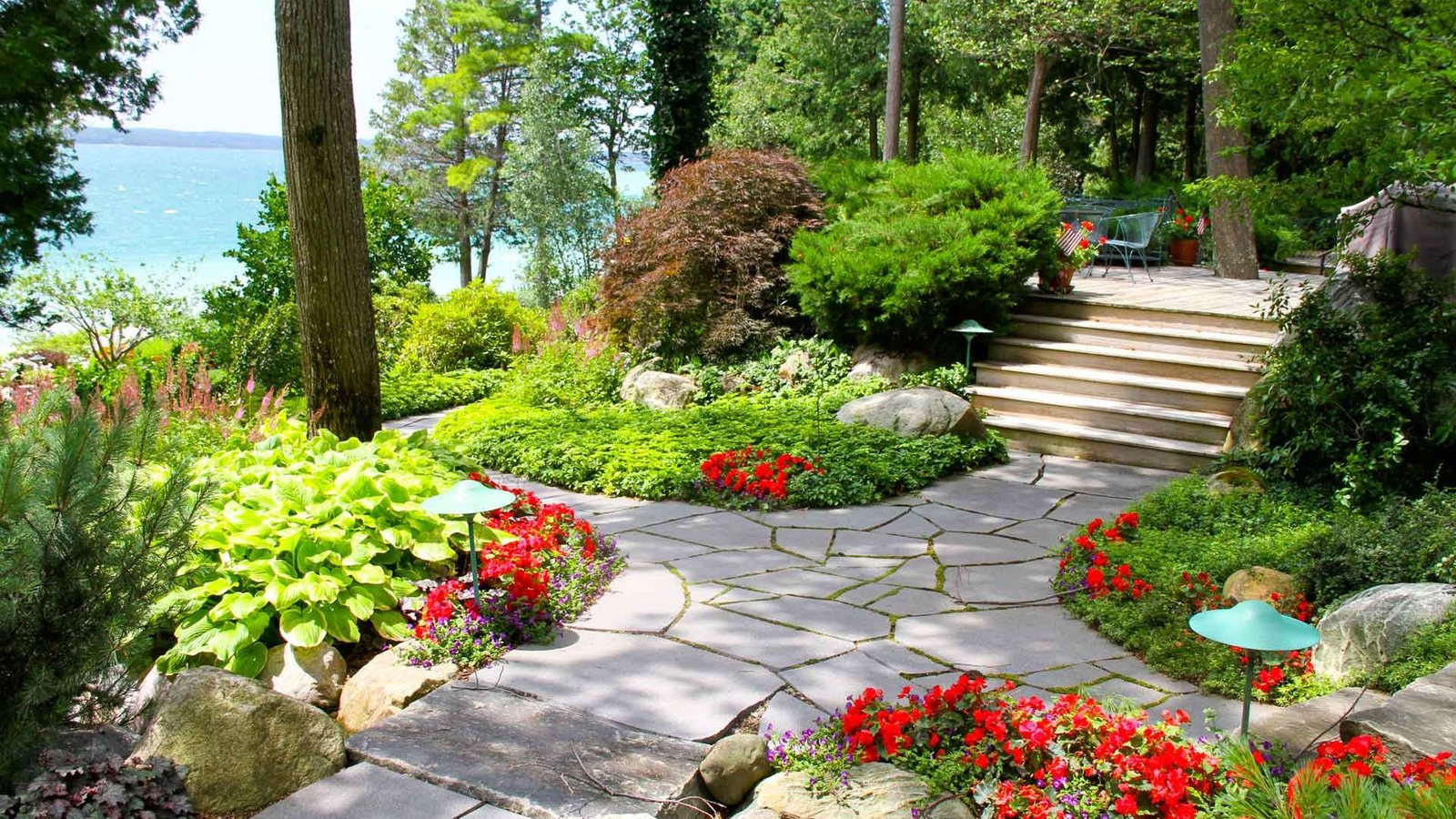 landscape stone walkway surrounded by green and red flowers